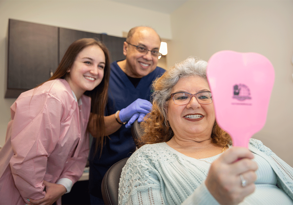 Dr. Radwan, patient, and staff smiling at the patient's new smile.