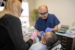 Dentist and dental assistant performing a dental procedure on a patient in a treatment room. The team works carefully to provide safe and effective dental care.